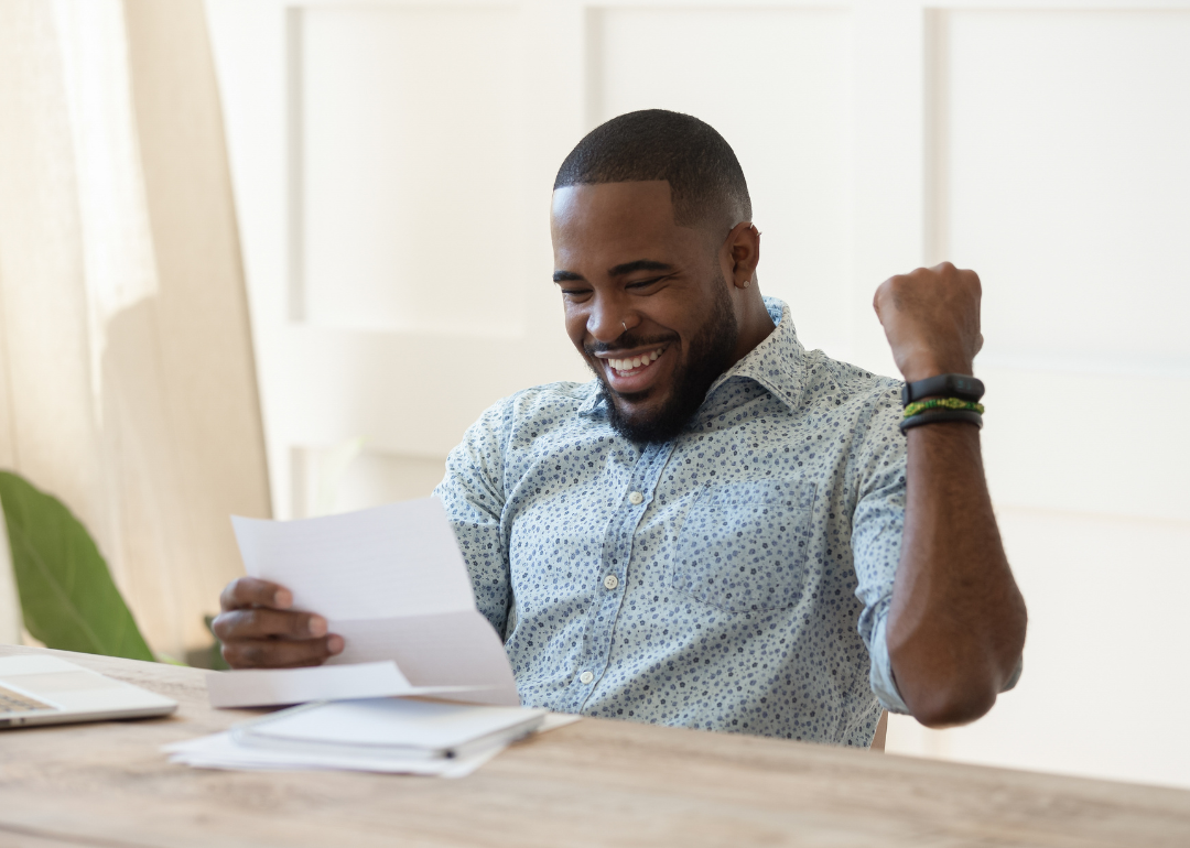 Excited person fist pumping the air while reading a letter