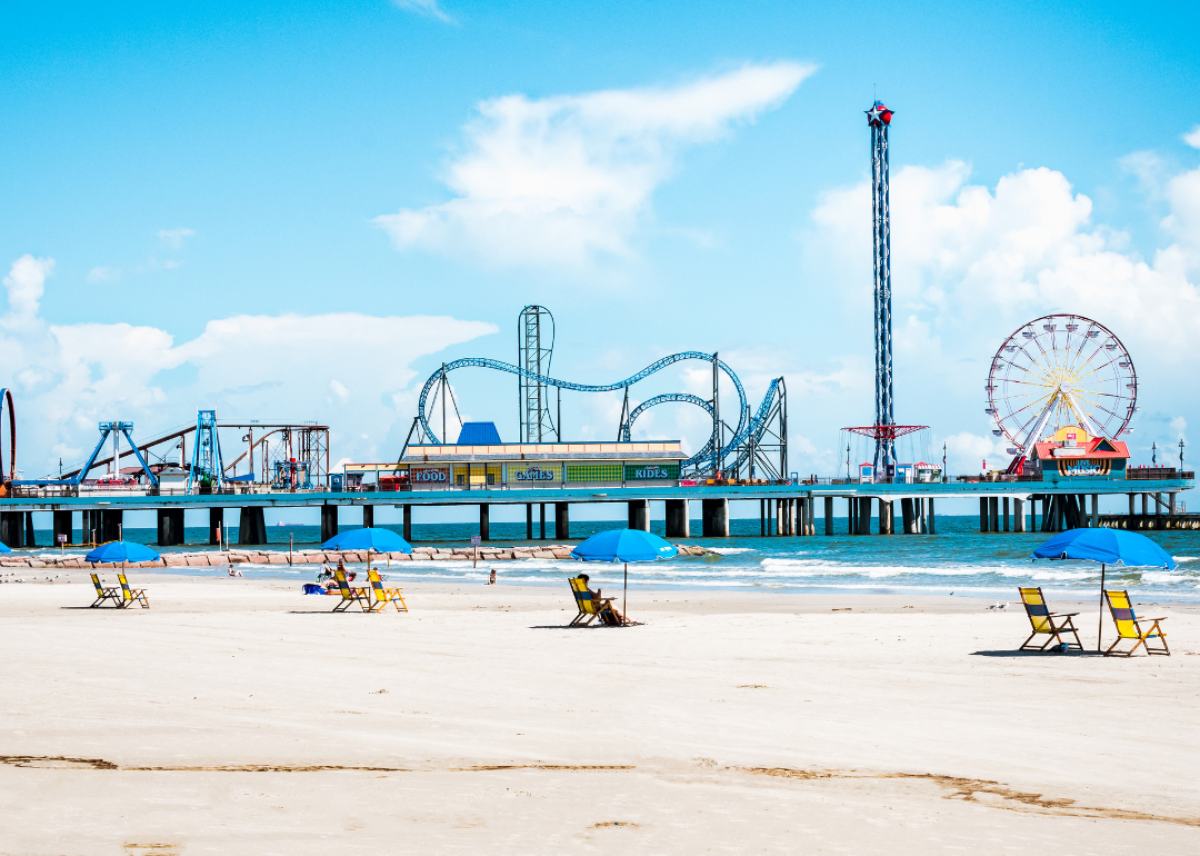 View of beach umbrellas and Pleasure Pier amusement park on Galveston Island, Texas.
