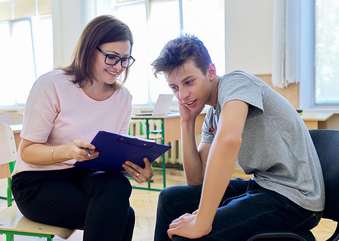 A woman counselor having a discussion with a teenage boy in school.