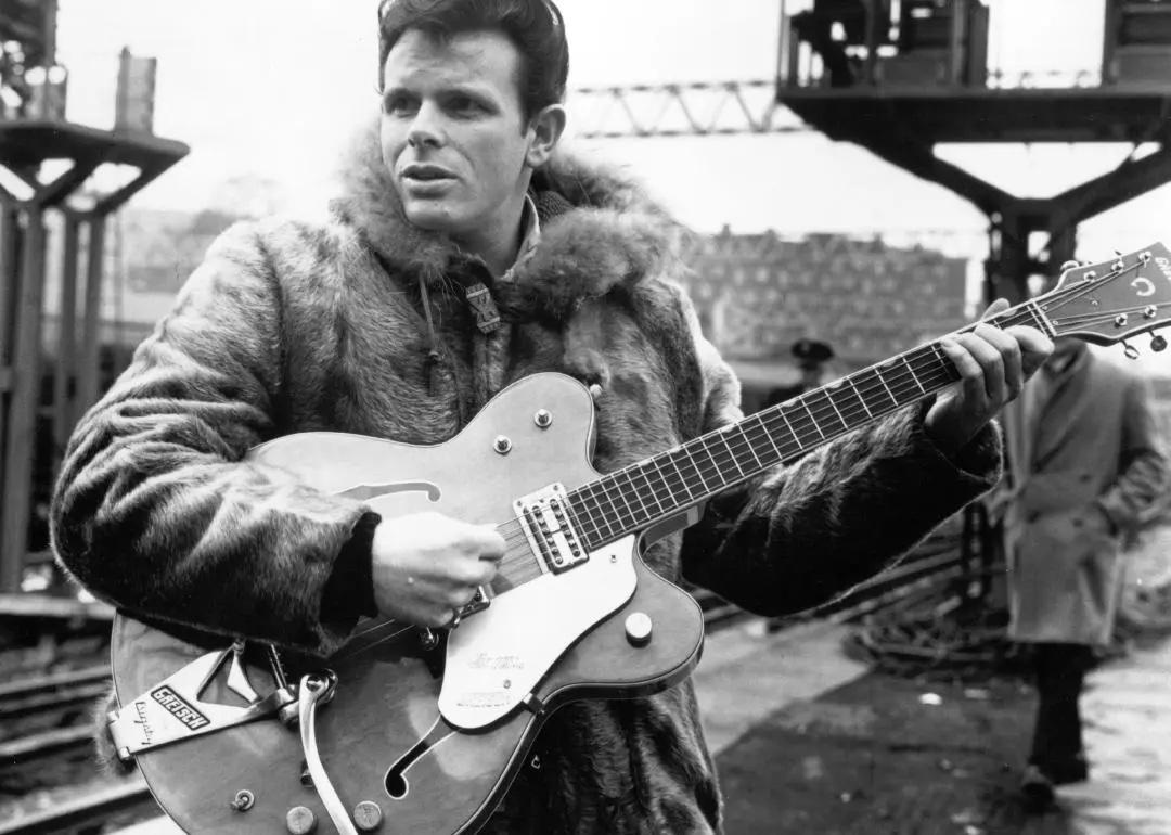 Portrait of rock singer Del Shannon holding guitar.
