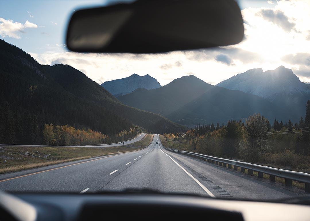 Road trip view of mountains and open road, from behind the wheel in car.