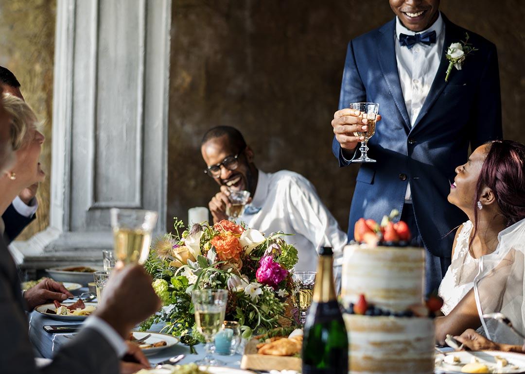 A photograph of a newly-wed couple raising a toast with wedding guests.