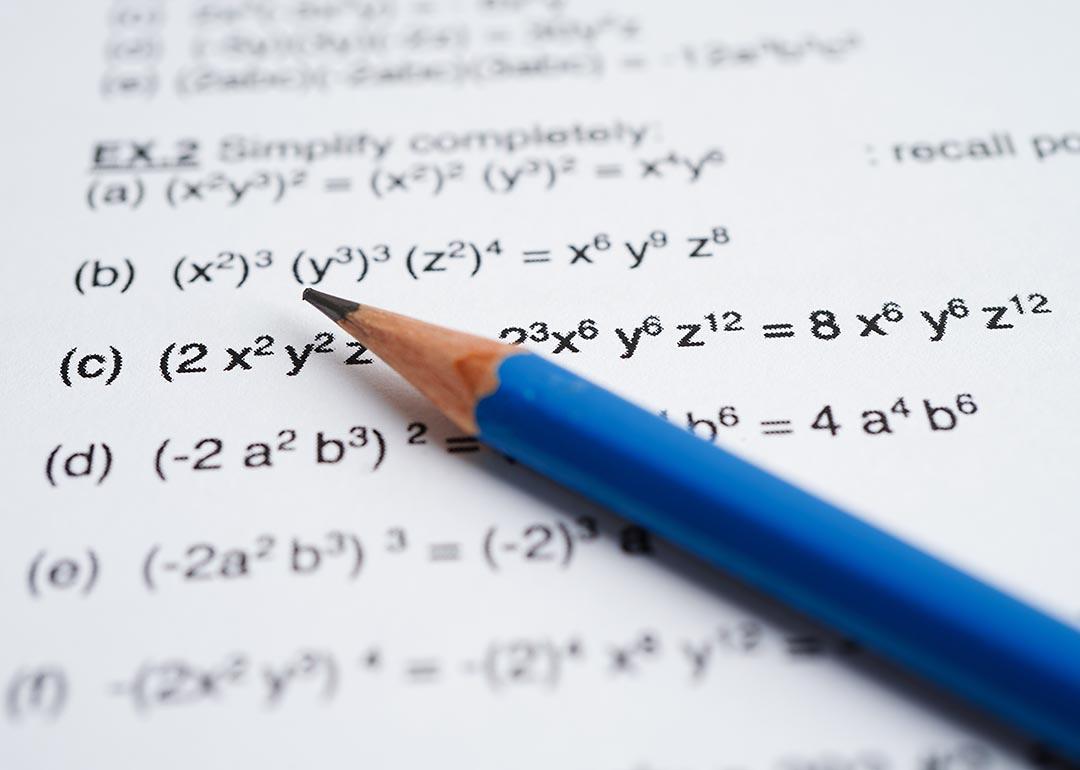 Blue pencil rests on page of algebra math problems. 
