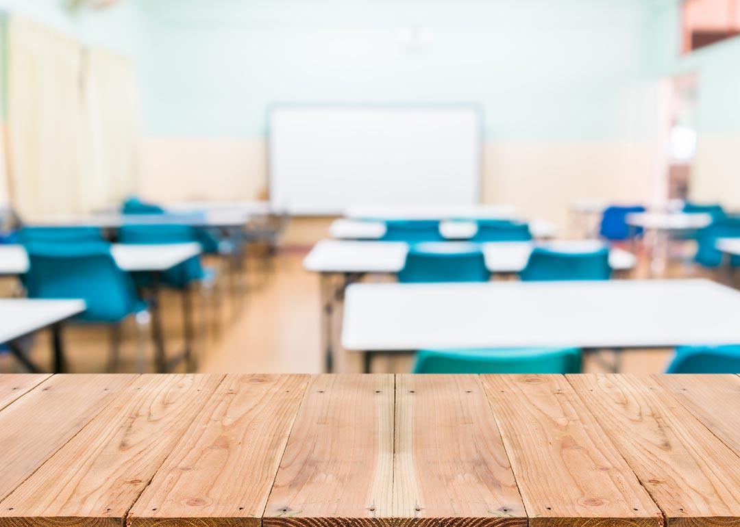 View of empty classroom with desks and blue chairs chairs and whiteboard.