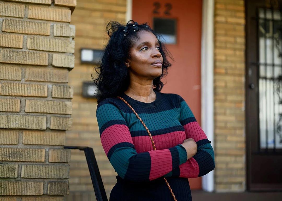 Portrait of Diane Lewis standing in front the apartment where she grew up in Connecticut.