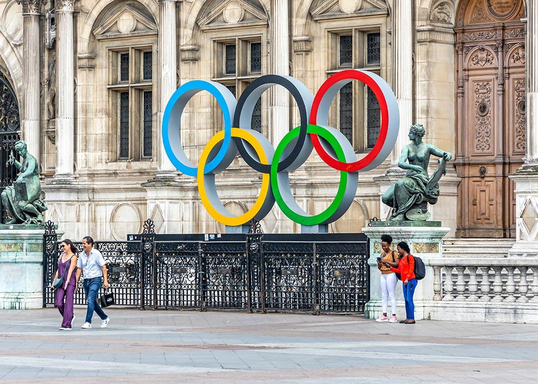 Tourists walking in the Hotel de Ville square with the Paris 2024 Olympic rings in front of the city hall in Paris, France.