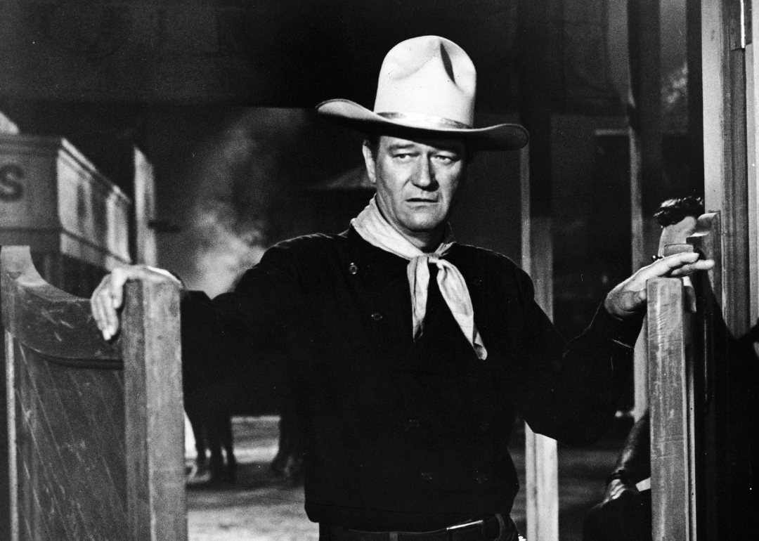 American actor John Wayne (1907 - 1979) wears a Western outfit which includes a pistol in a holster and stands in a doorway in a still from the Cowboy film 'The Man Who Shot Liberty Valance' directed by John Ford, 1962.