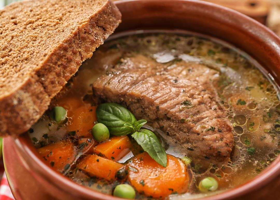 Crock pot with stewed meat and vegetables with a slice of bread