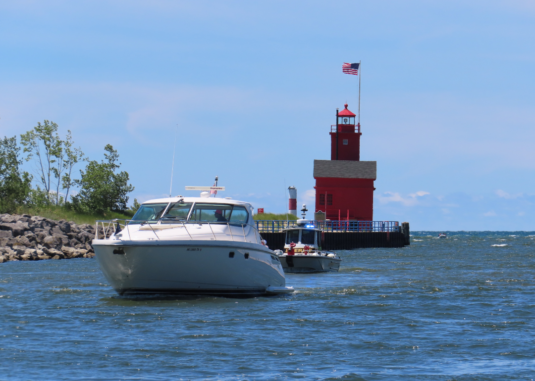 Boat cruising up the inlet of Lake Michigan with the iconic Big Red Lighthouse in the background in Holland, Michigan