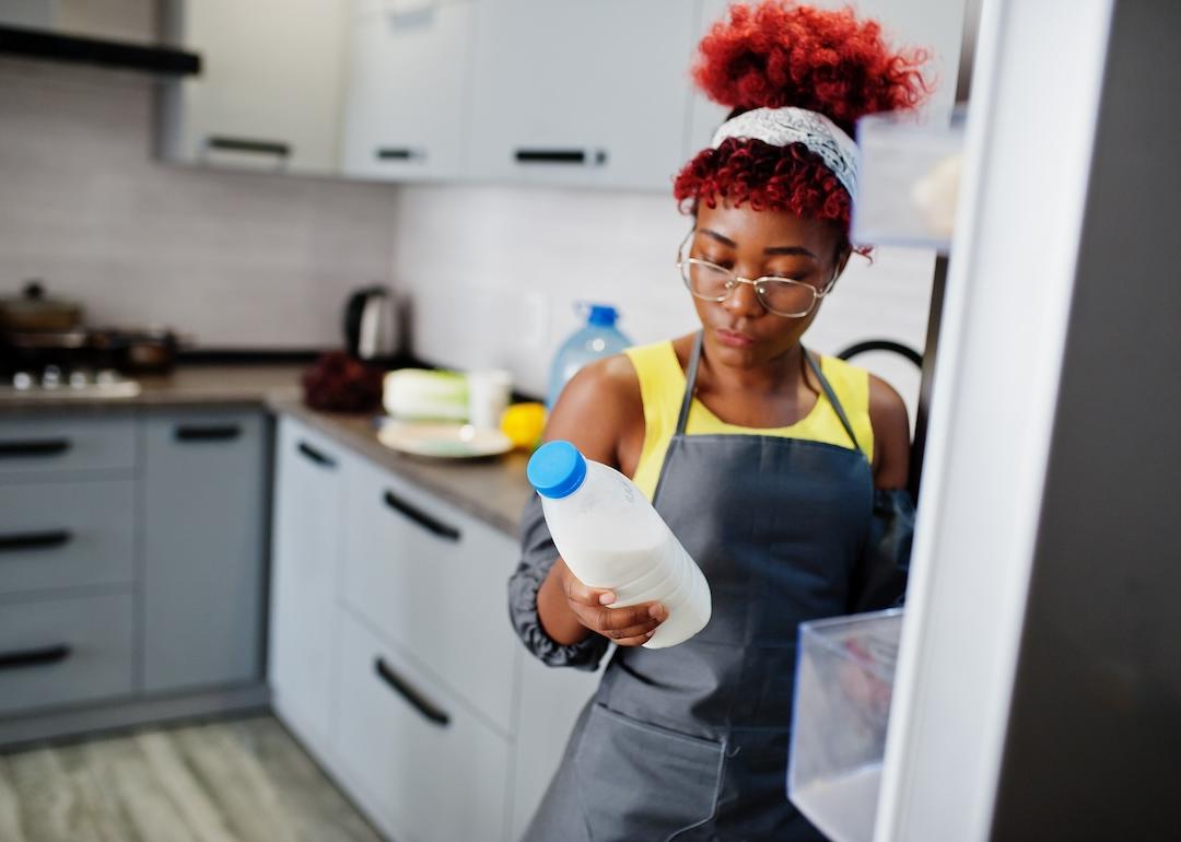 Woman holding a carton of milk from the refrigerator.