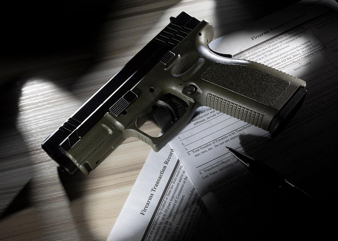 Gun resting on forms for background checks.