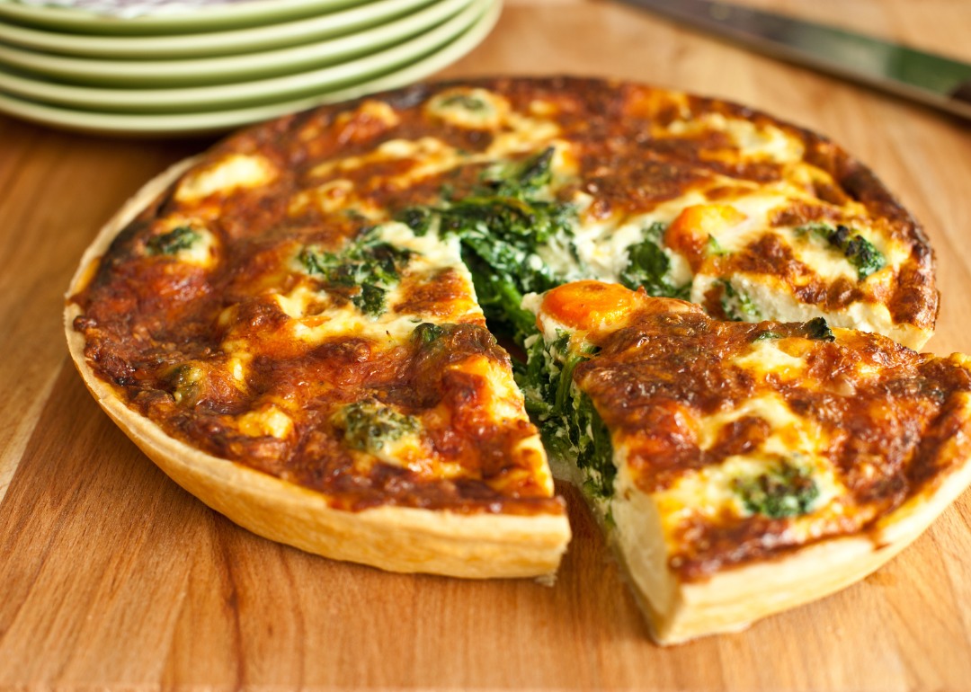 A freshly baked spinach quiche on a wooden kitchen counter