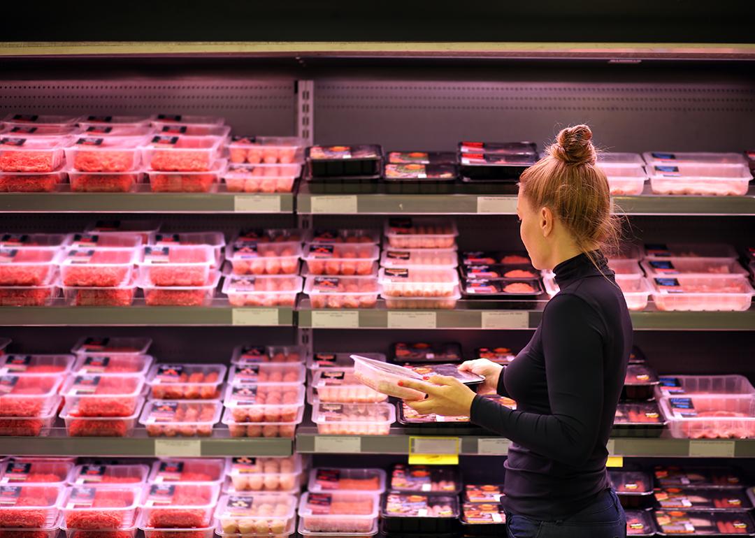 A woman shopping in the meat section of a supermarket.