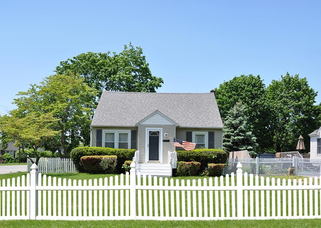 White picket fence in front of small bungalow house.