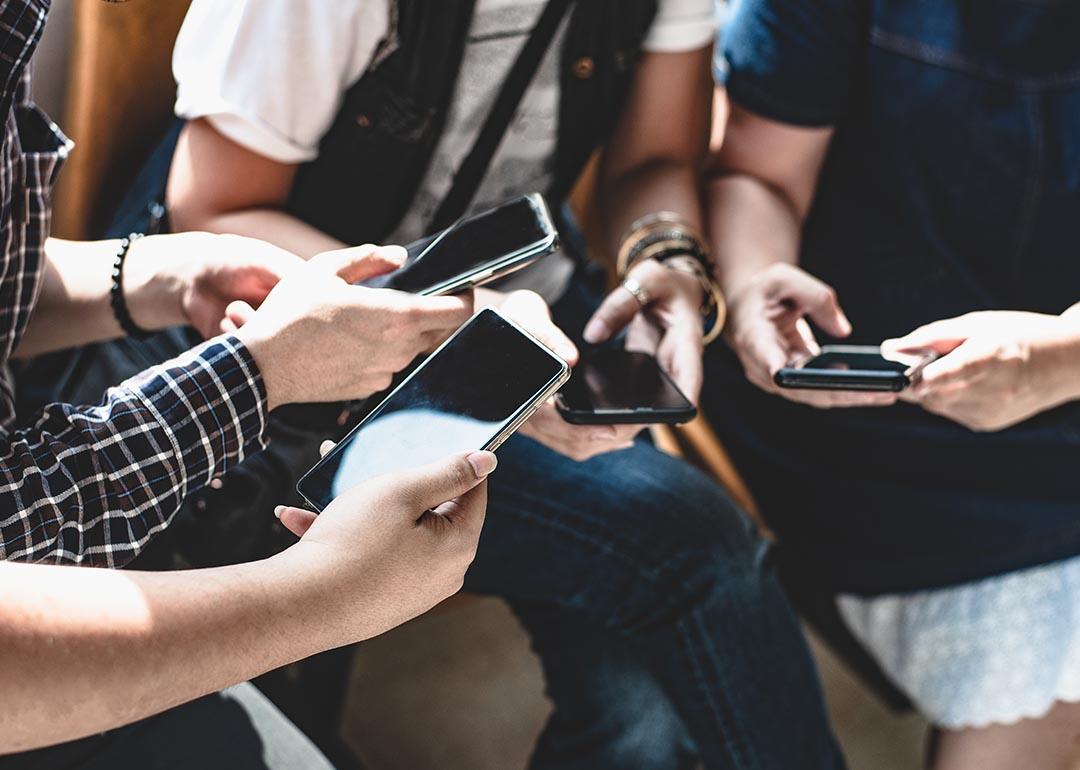 View of hands of group of young people using smart phones.