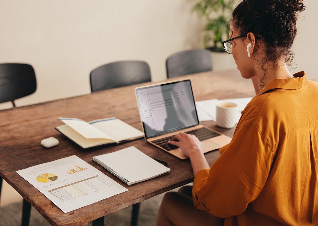 A busy young woman working from home with documents and notes in her table.