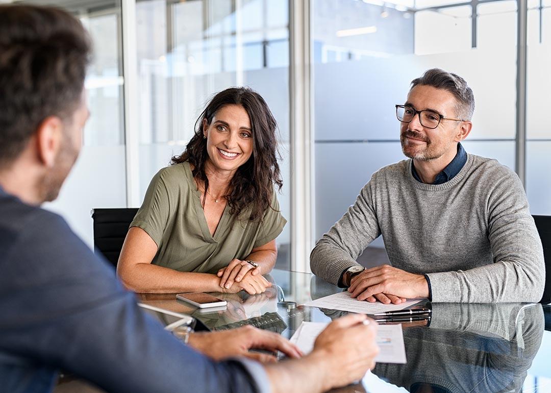 Smiling mature couple meeting with financial advisor.