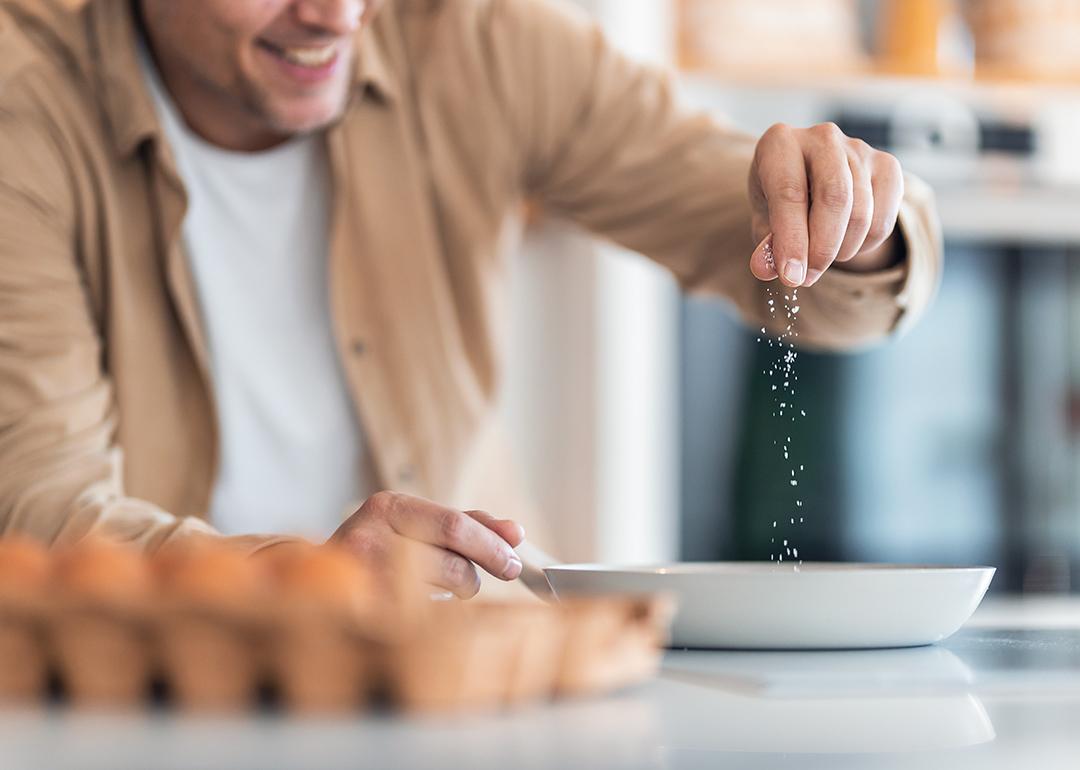 A man seasoning egg mixture with plenty of salt.