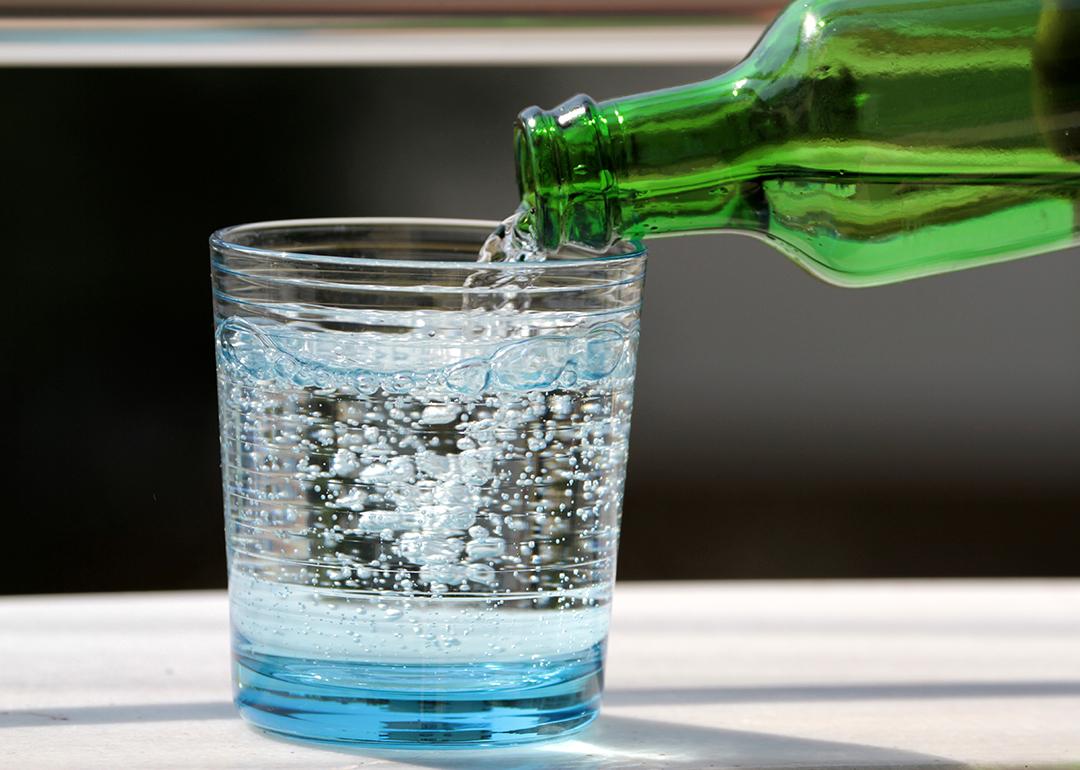 Sparkling water poured onto a glass from its bottle.