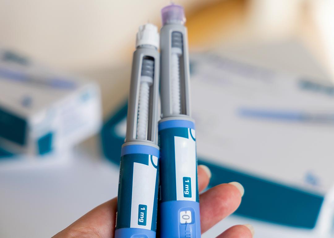 A hand holding two Ozempic pens for diabetics.
