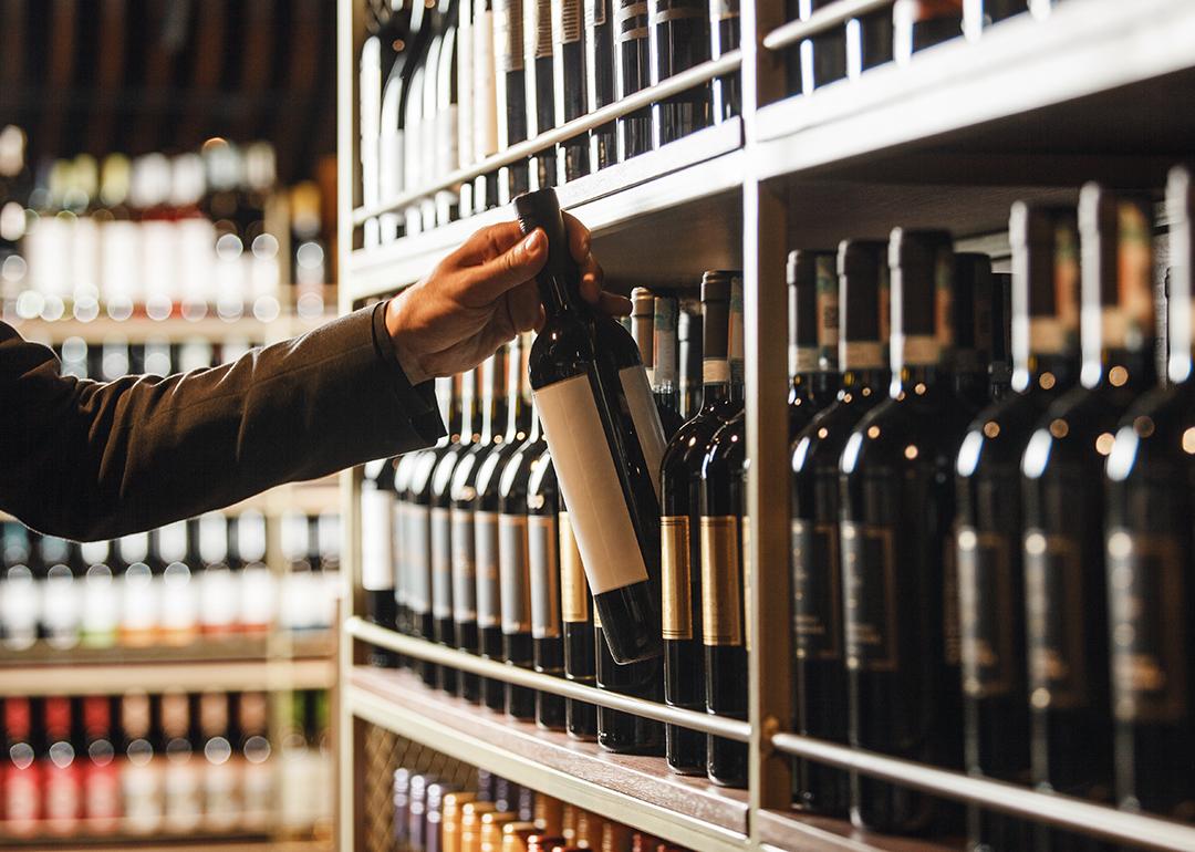 An extensive wine cellar collection and a wine bottle is being carefully picked.