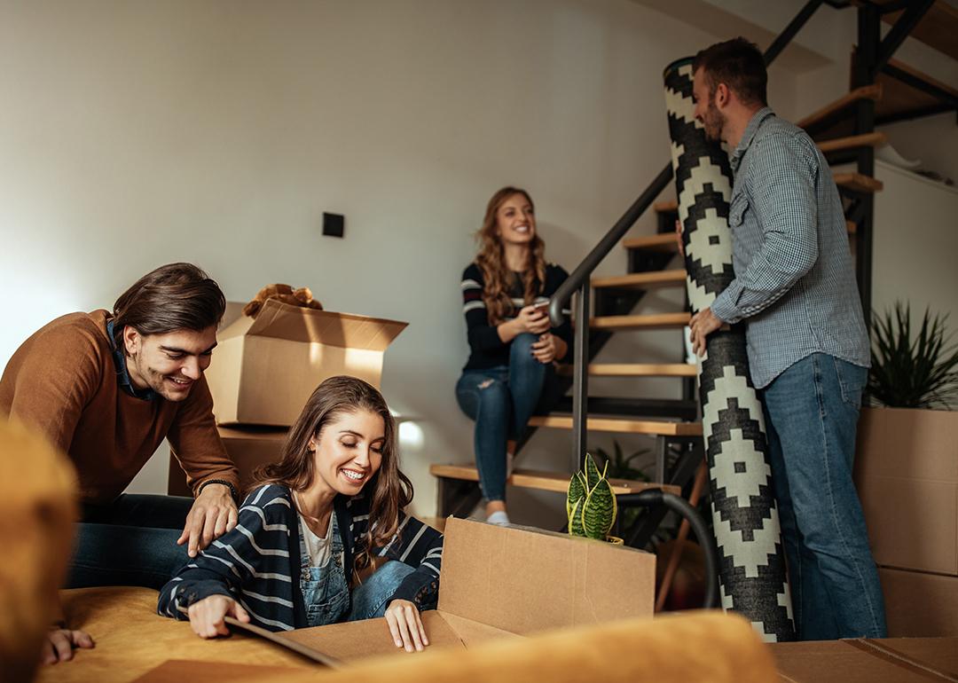 Four people who are co-living in a house are unpacking boxes of home items.