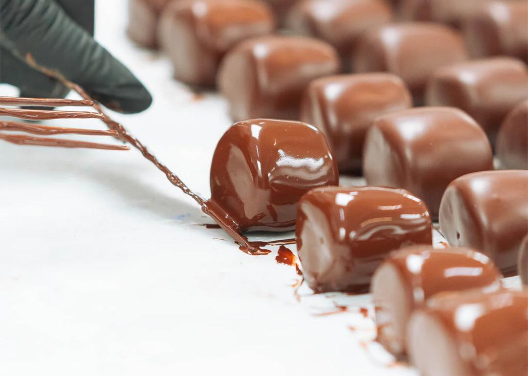 Chocolate covered marshmallows being prepared in rows.