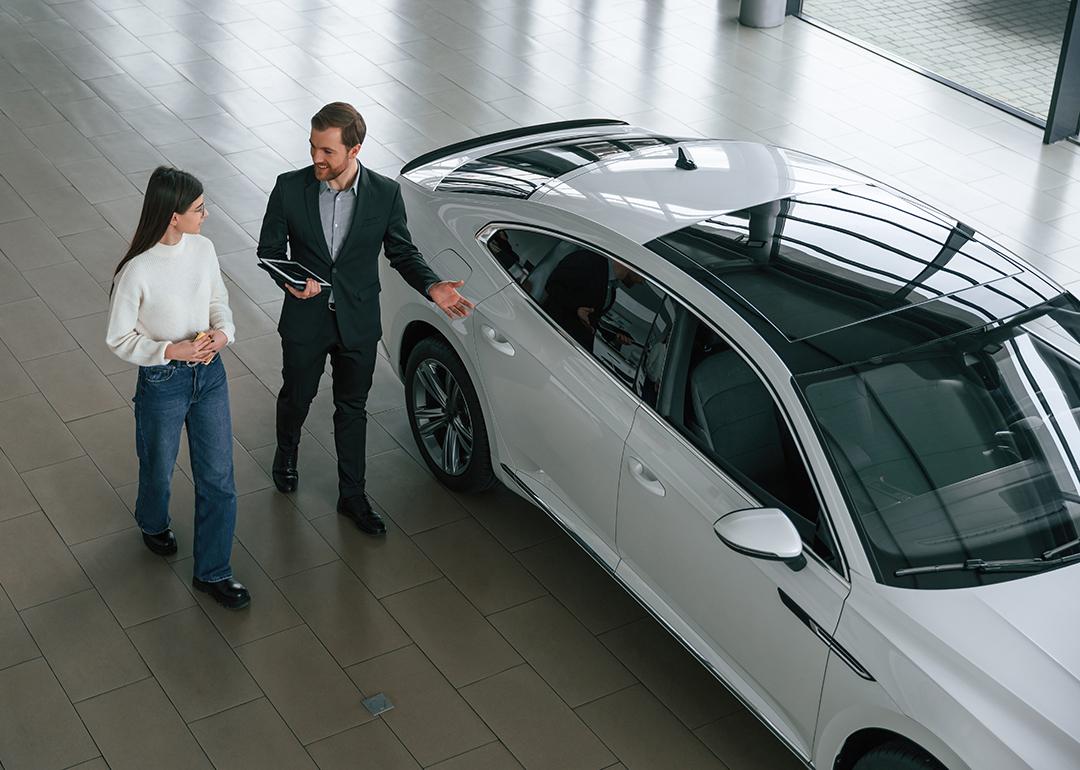 A woman choosing a new car in a dealership while an agent assists.