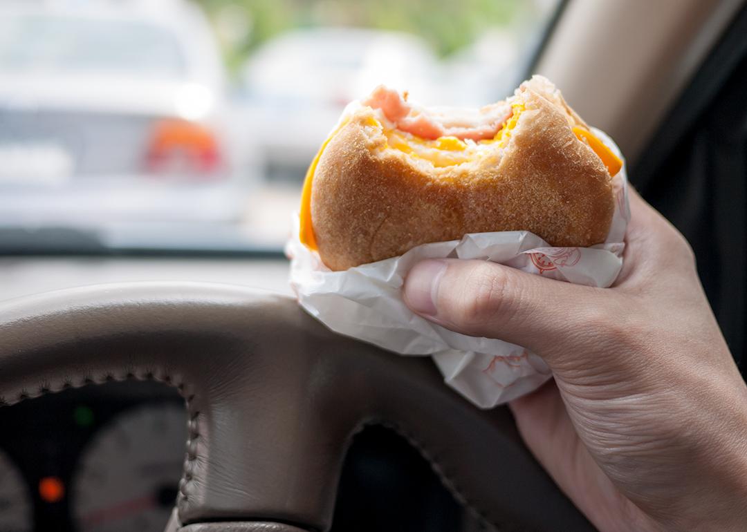 A breakfast sandwich being eaten inside the car during morning traffic.