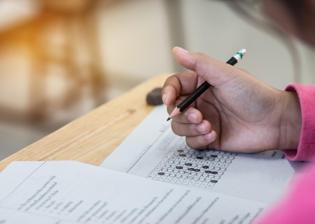 A student in a pink top filling out an answer form on an assessment test.