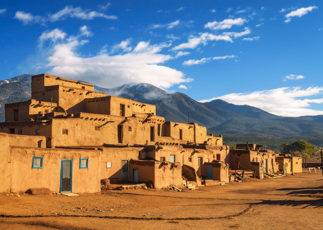 Ancient dwellings of UNESCO World Heritage Site Taos Pueblo in New Mexico with mountains in the background.