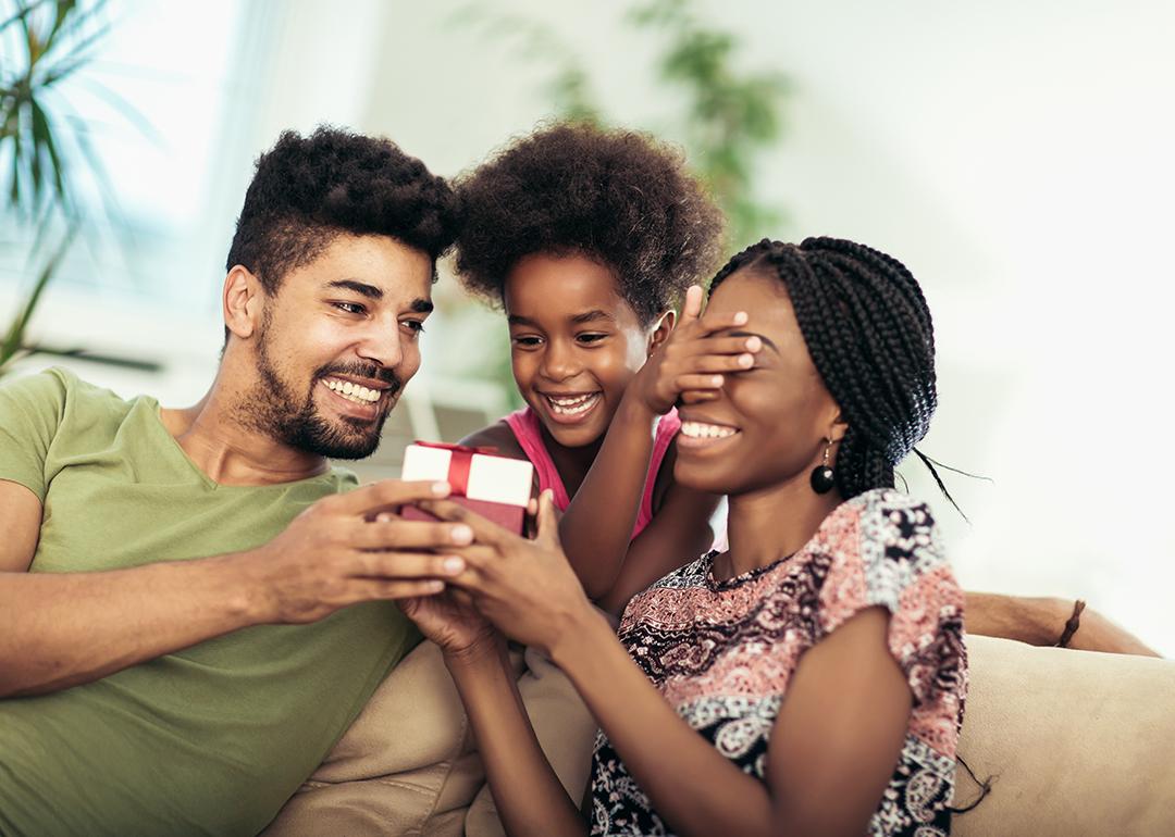 A happy black family surprising the mother with a box of jewelry as a mother's day gift.