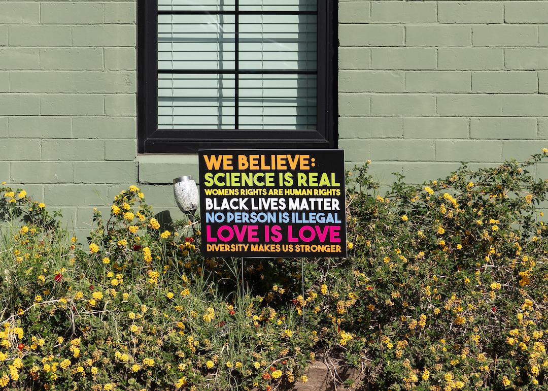 "We believe" yard sign that says, "Science is real, womens rights are human rights, black lives matter, no human is illegal, love is love, diversity makes us stronger” outside of a green home.