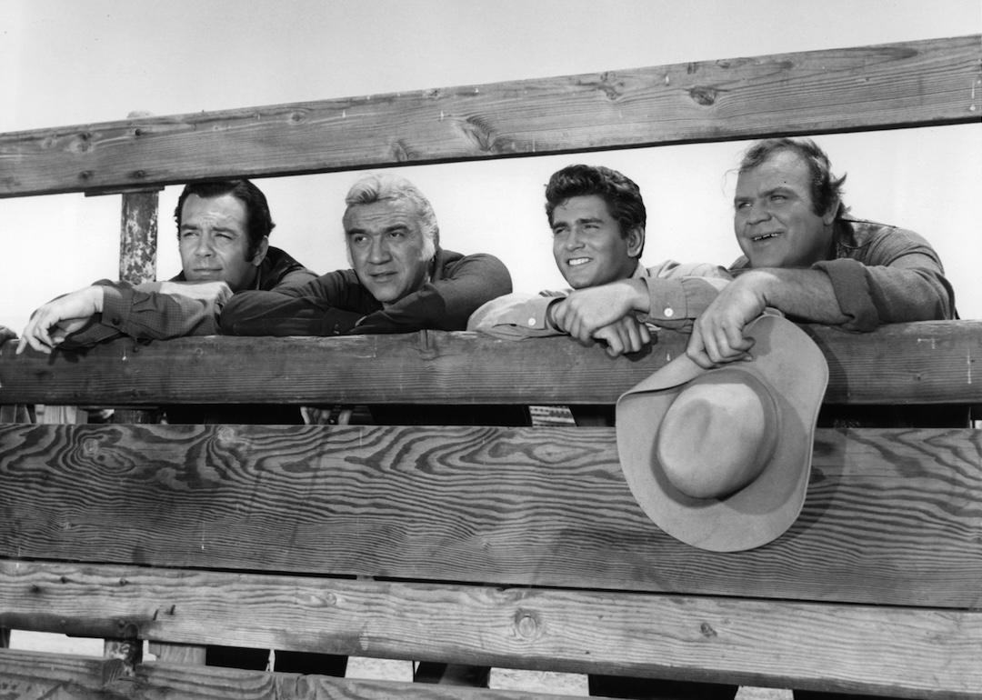 Dan Blocker holds his hat while standing with others in a scene from the TV series “Bonanza” (1959–1973).