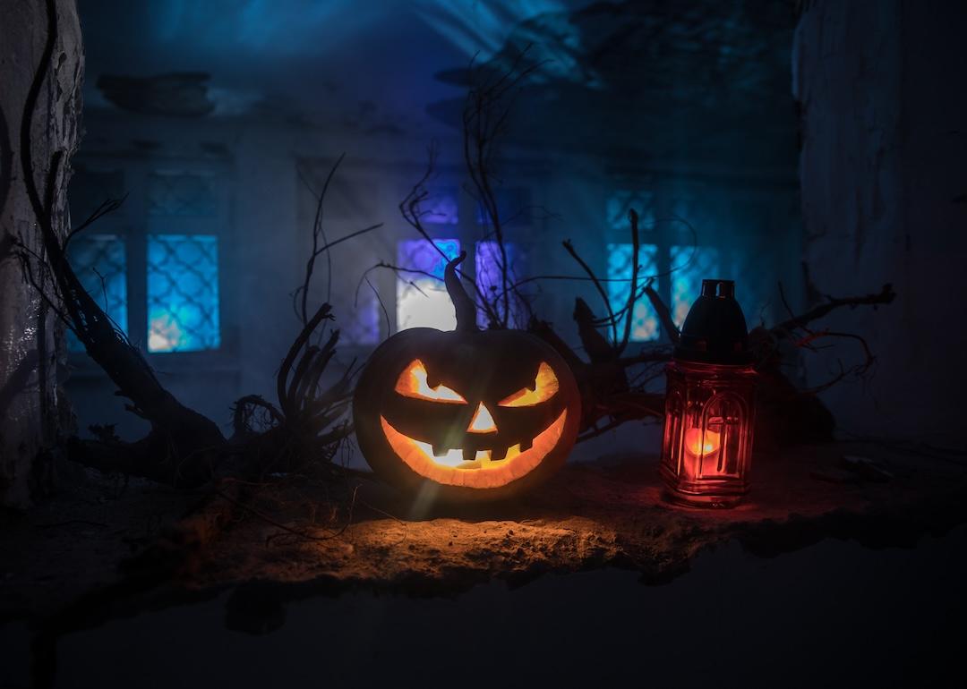 Scary Halloween pumpkin with a spooky house in the distance.