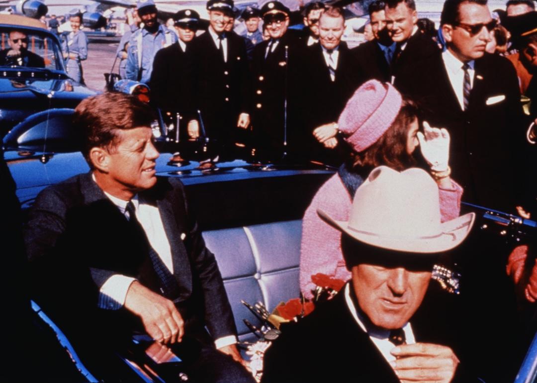 Texas Governor John Connally adjusts his tie as President John F. Kennedy and First Lady Jacqueline Kennedy settle into the rear seats of their car before the Dallas motorcade on November 22, 1963.