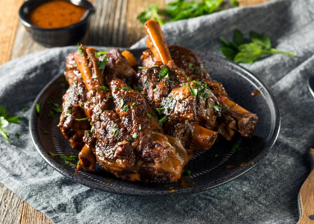 Homemade braised lamb shanks with sauce and herbs.