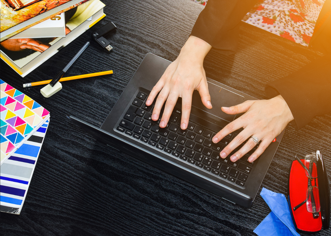 An overhead view of a student typing on a laptop surrounded by school supplies.