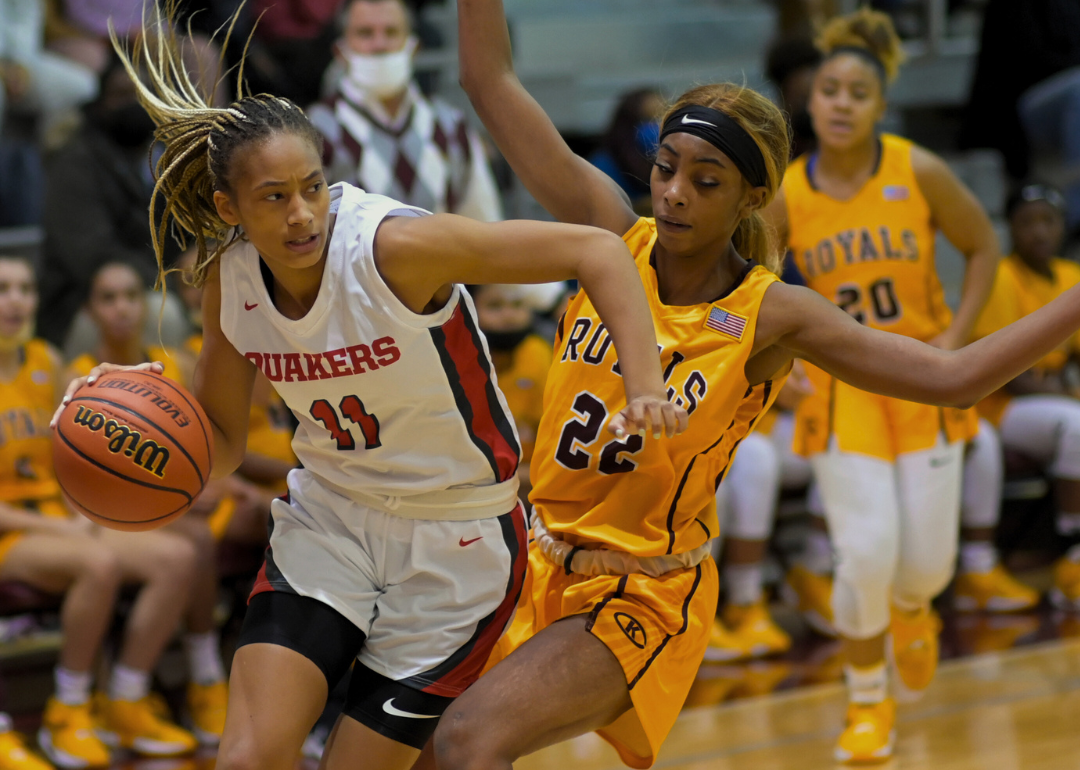 Two basketball players on a basketball court during girls basketball tournament. 