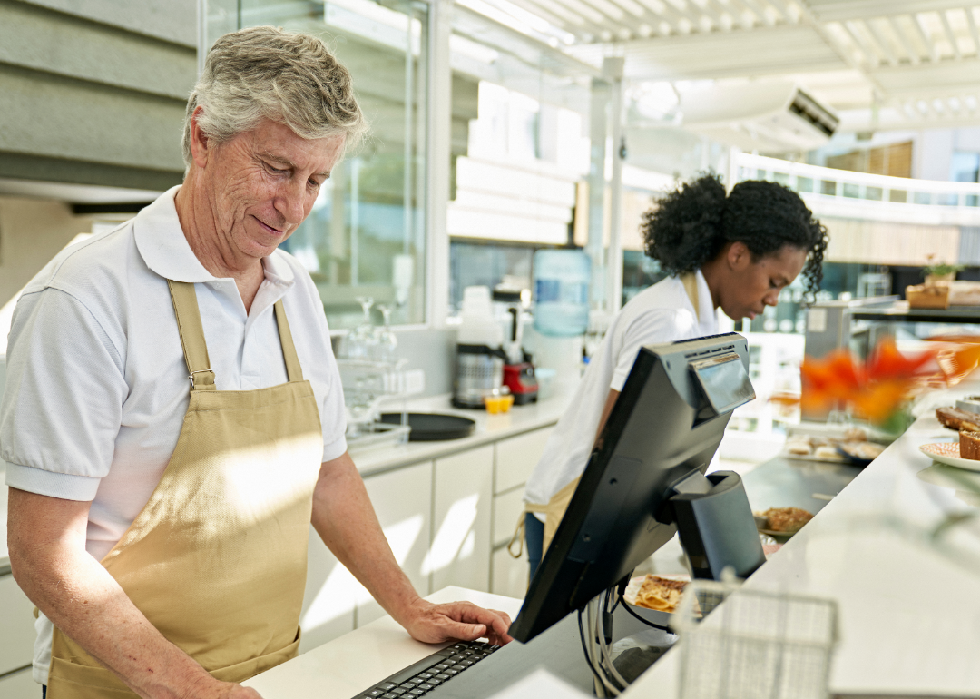 Two food service workers work behind a counter.