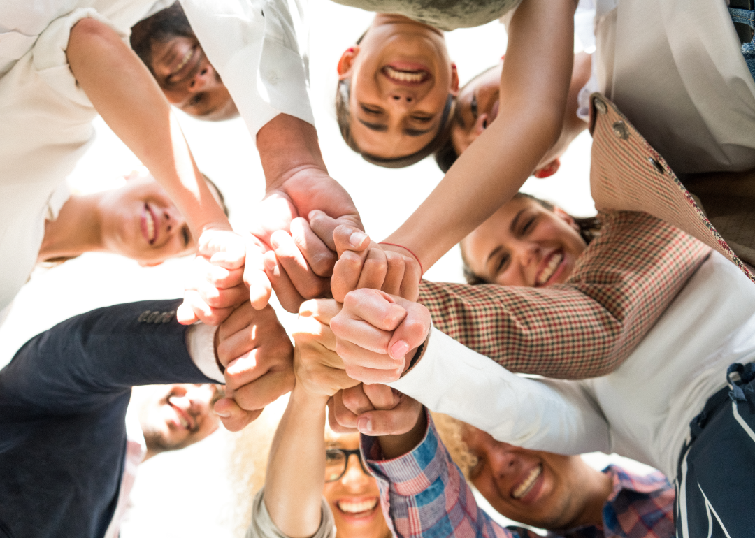 People smiling with their hands touching in the middle of a circle.
