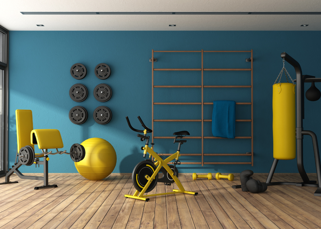 A home gym with fitness equipment, including weights on the wall, a weight bench, an exercise ball, a stationary bike, and punching bag.