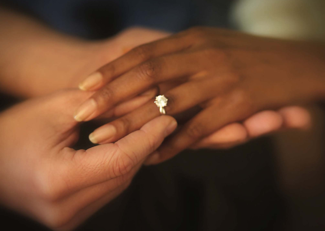 Two hands together with an engagement ring.