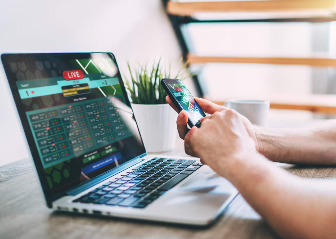 Close-up of a person placing sports bets on a laptop.