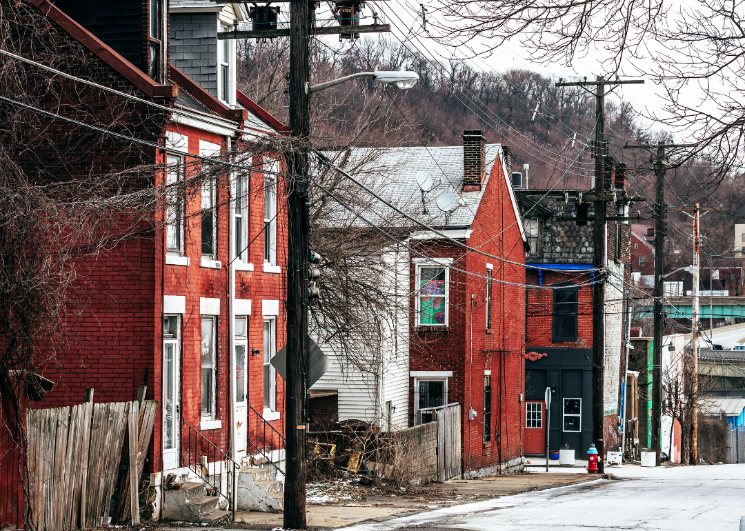 A row of brick houses with messy front yards and power lines in front of the buildings. 