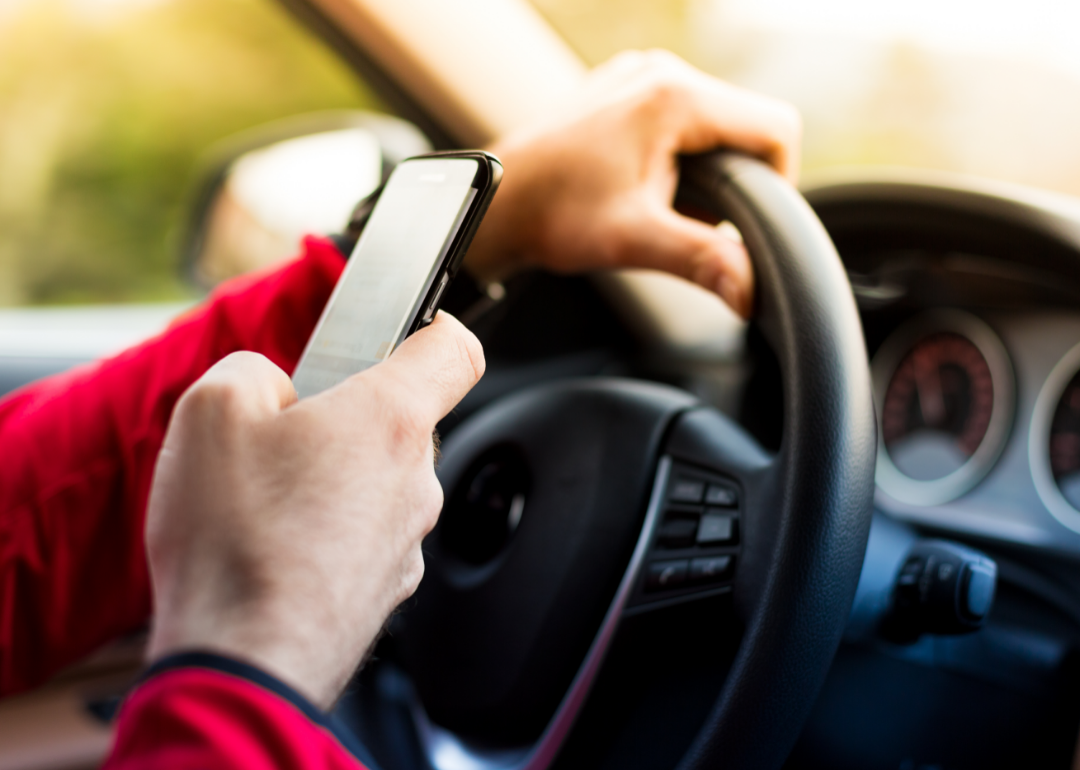 Driver with one hand on the steering wheel and one hand texting
