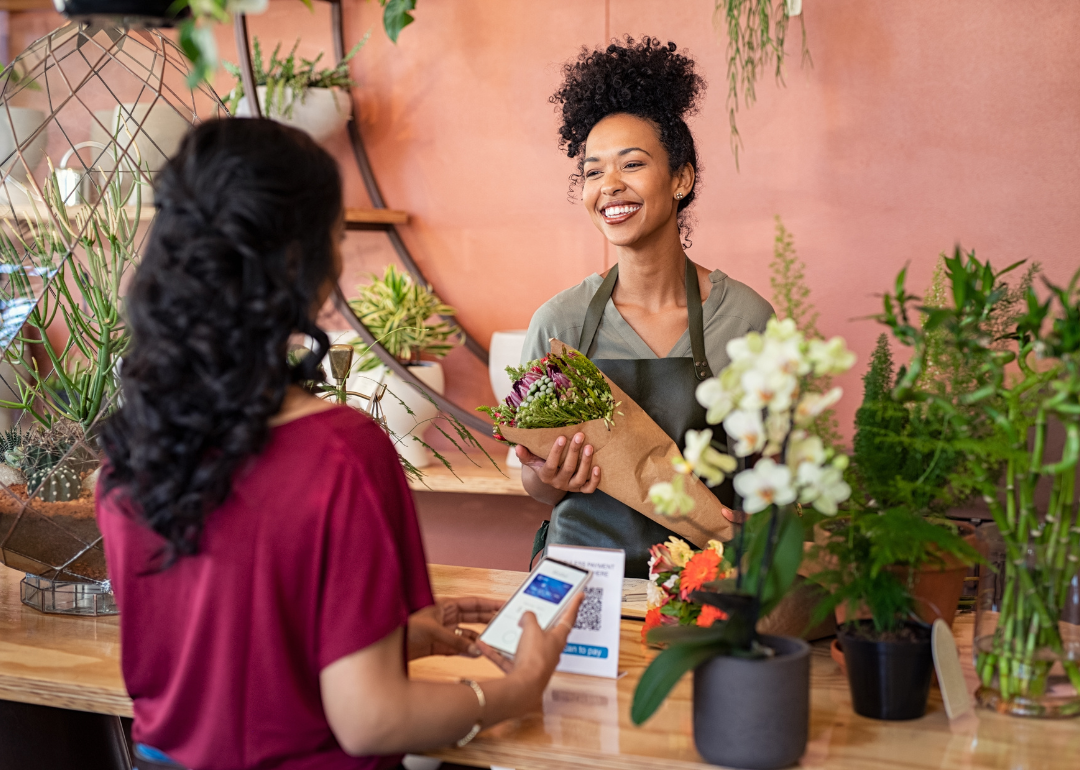 A florist handing flowers to a customer who has just scanned a QR code.