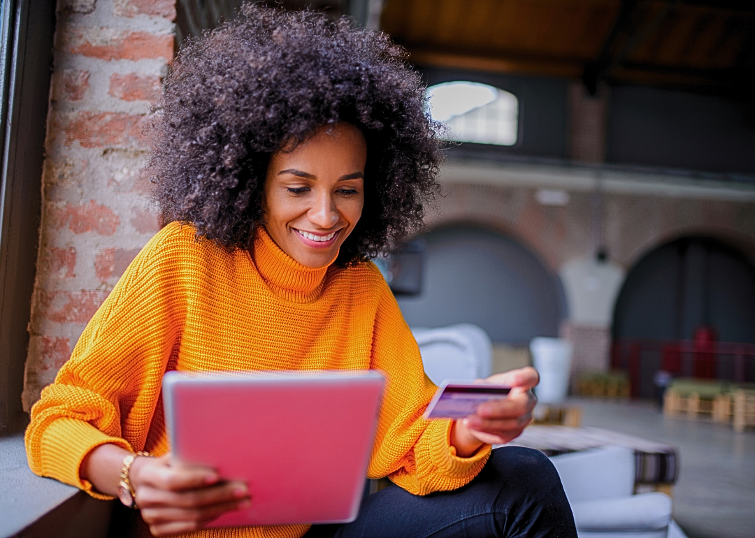 Young Black woman with an iPad and a credit card in her hand.