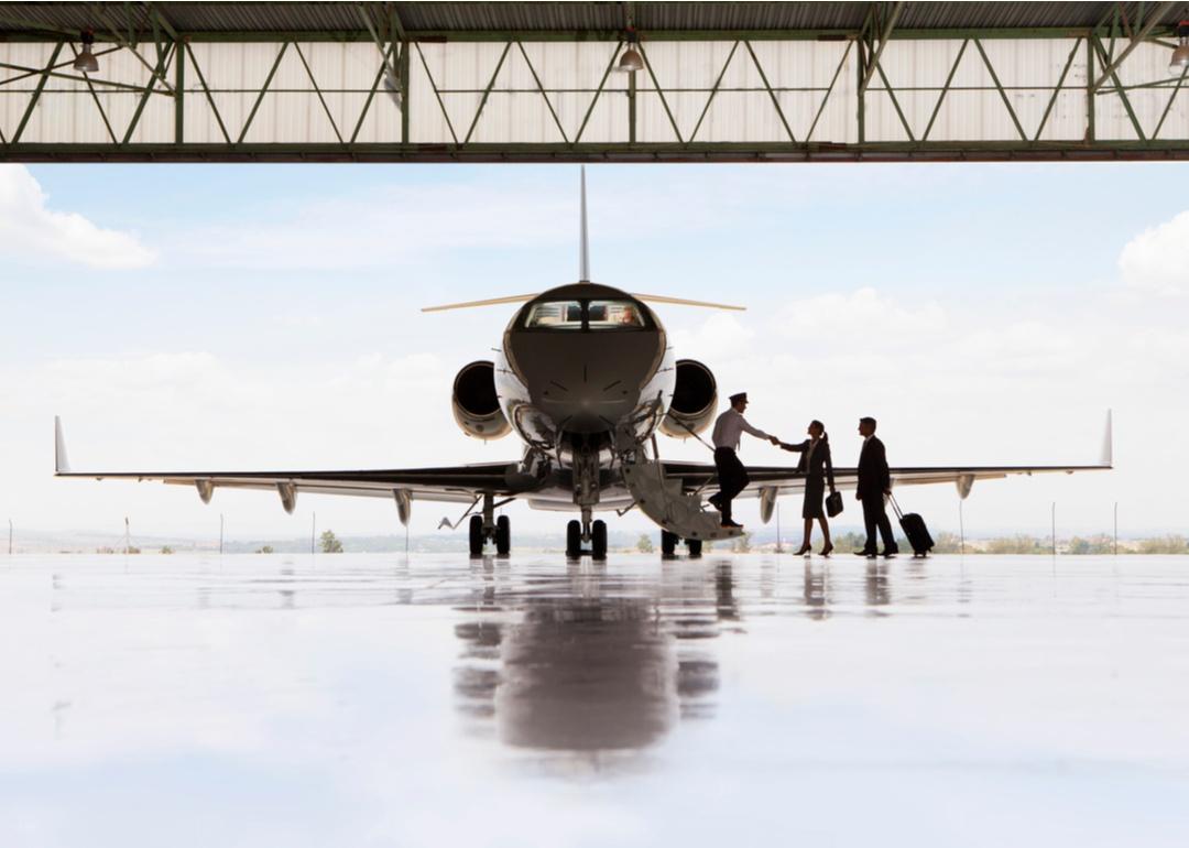 Silhouette of smaller aircraft with pilot and staff shaking hands and boarding.