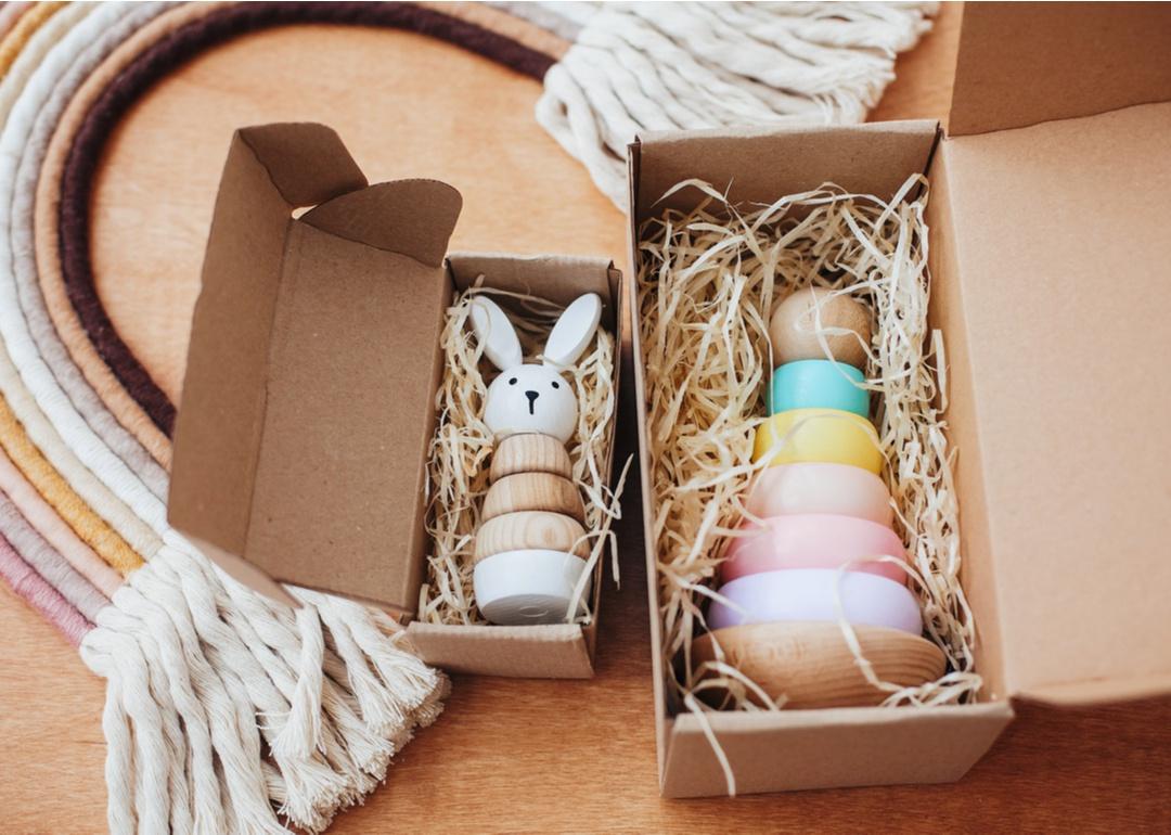 Wooden baby toys in boxes in front of a rainbow toy made of rope.